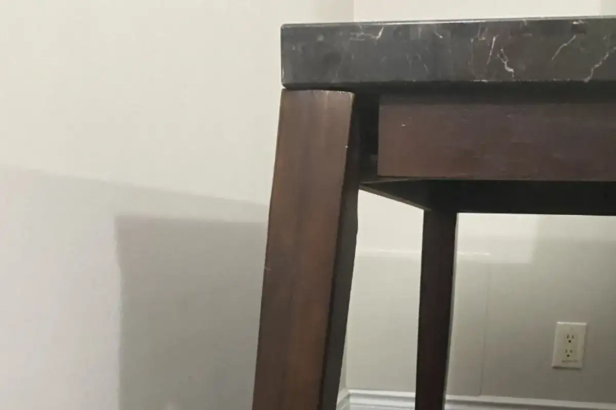 Loose wooden table leg slightly separated from the tabletop frame due to weakened screw connections