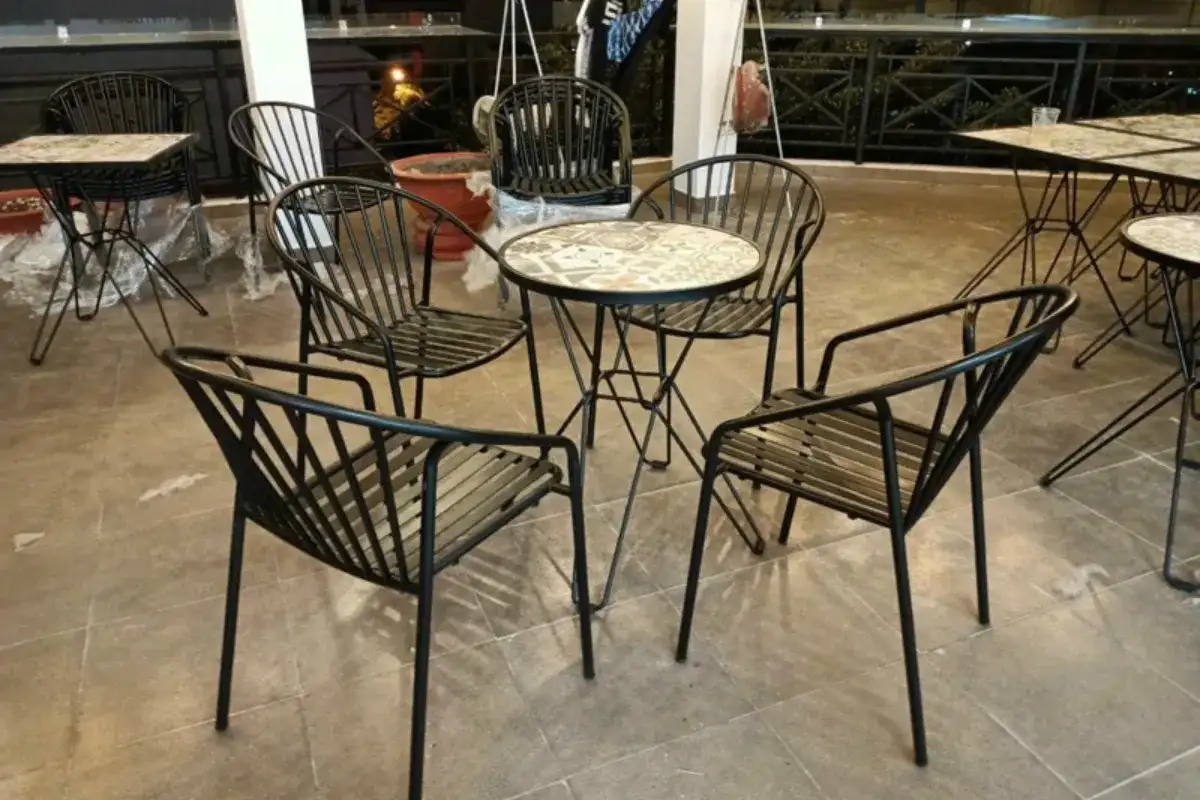 Bộ bàn ghế cafe CoCa bằng sắt với bàn tròn và khung kim loại thanh mảnh đặt trên sân ngoài trời