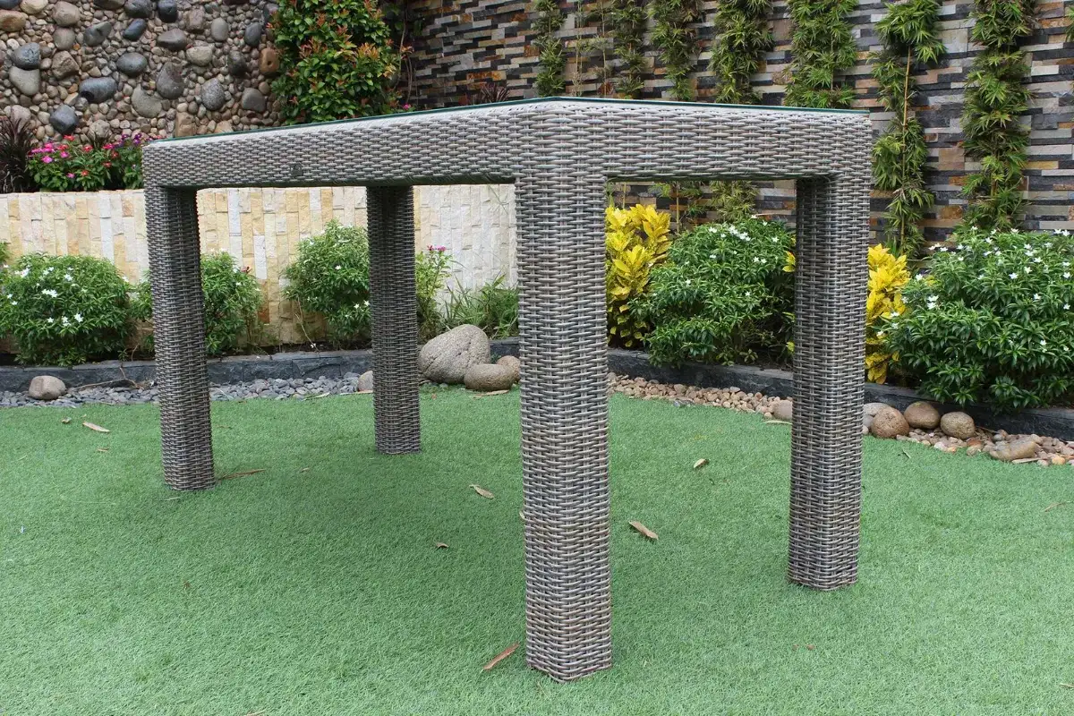 Synthetic rattan outdoor high table with woven gray surface in a garden setting