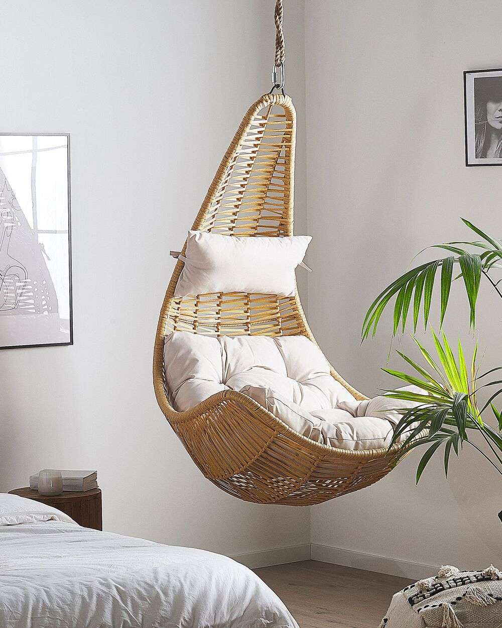 White nest-like hanging wicker chair with soft cushions.