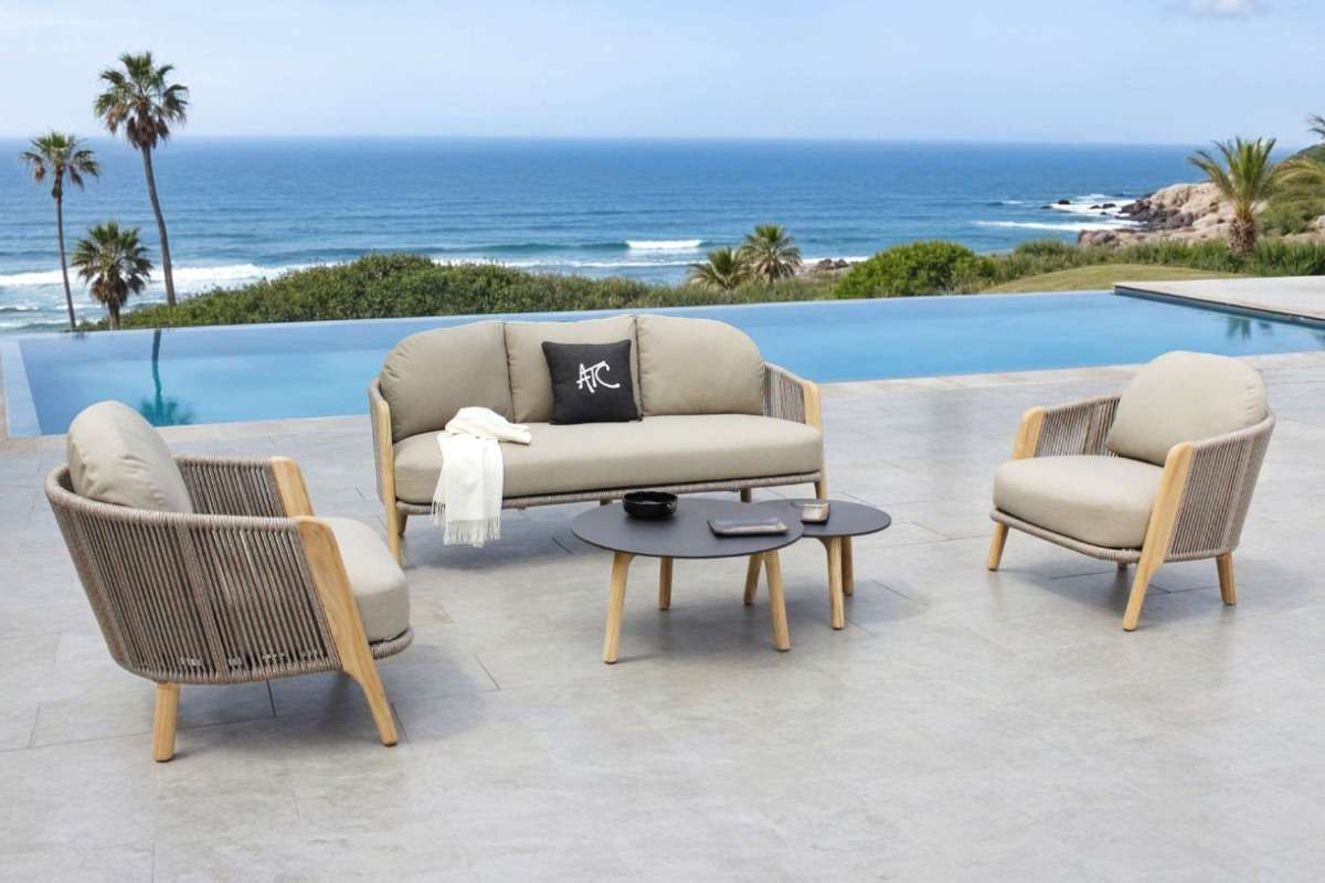 A 4-seater outdoor sofa set placed facing the ocean and infinity pool in a modern villa setting.
