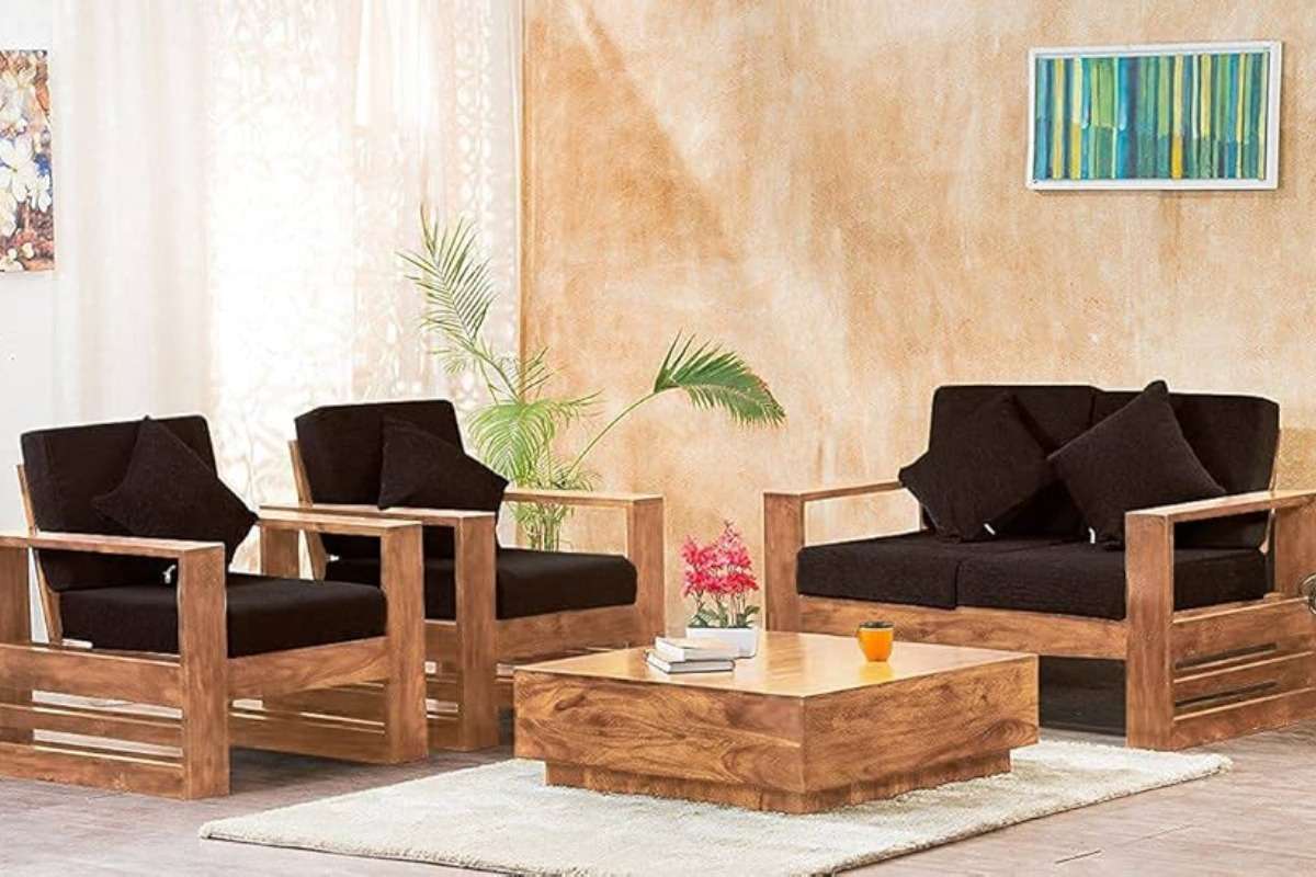 Teak wood 4-seater sofa set with rich brown cushions in a warm, tropical-inspired indoor living space.