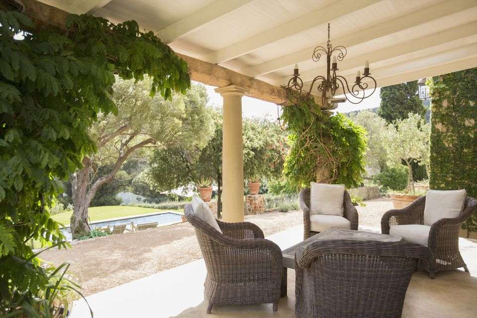 Outdoor wicker chairs placed under a spacious pergola