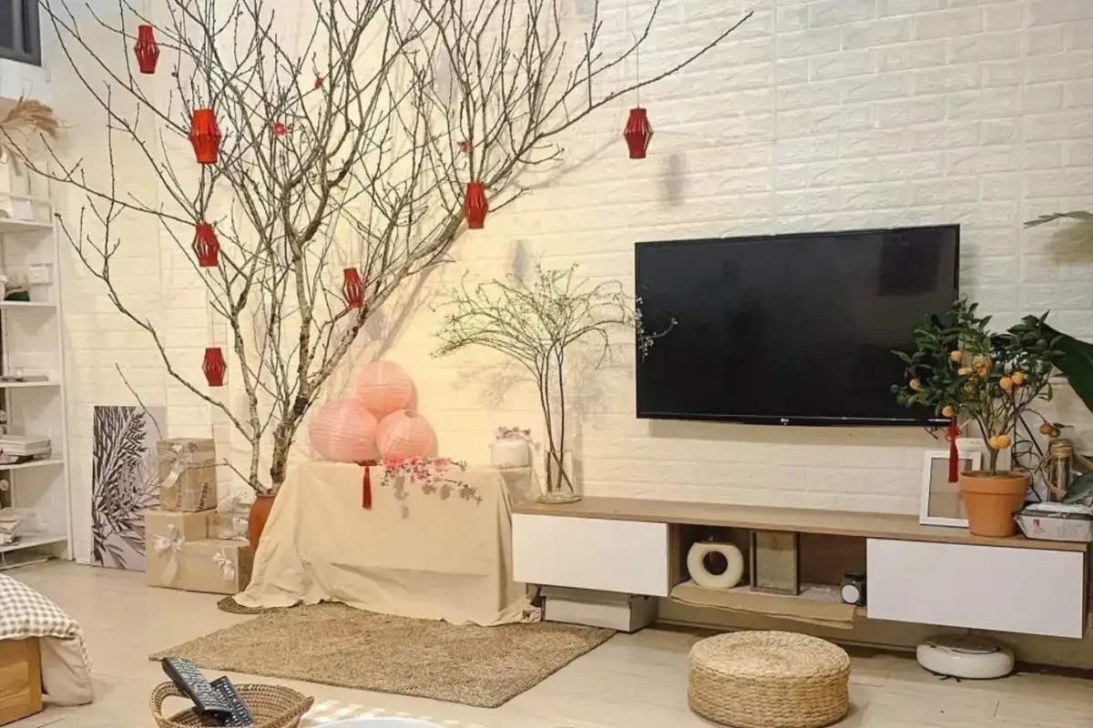 Không gian phòng khách trang trí Tết tối giản với cành cây khô, lồng đèn đỏ treo, đèn lồng giấy hồng và tông màu trung tính