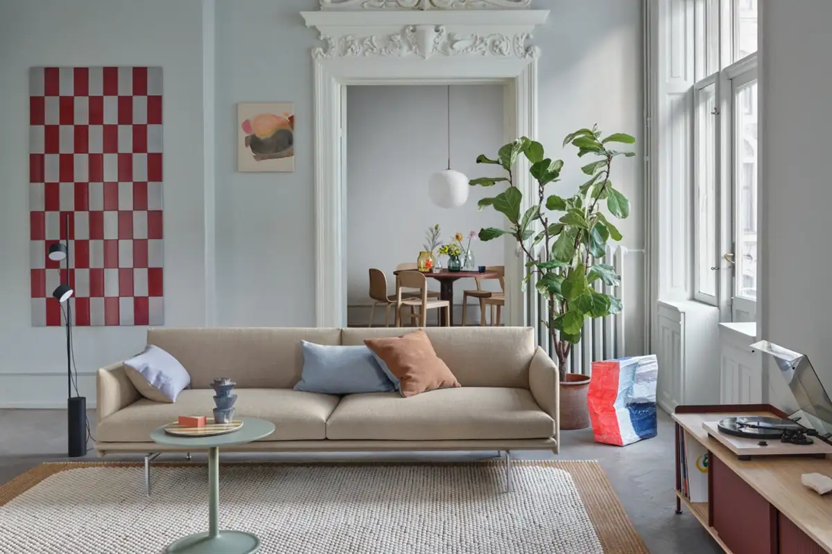 A clean and relaxed living space featuring Scandinavian minimalism with neutral sofa, soft textures, modern art, and an inviting corner by the window.