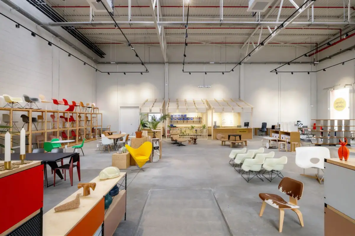 Interior view of a contemporary Vitra showroom showcasing iconic furniture designs in a large, open industrial setting with curated displays.