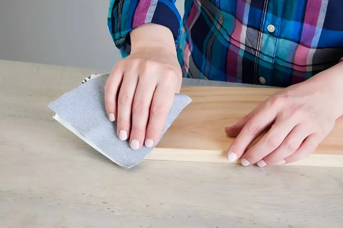 Smoothing the surface by sanding along the wood grain.