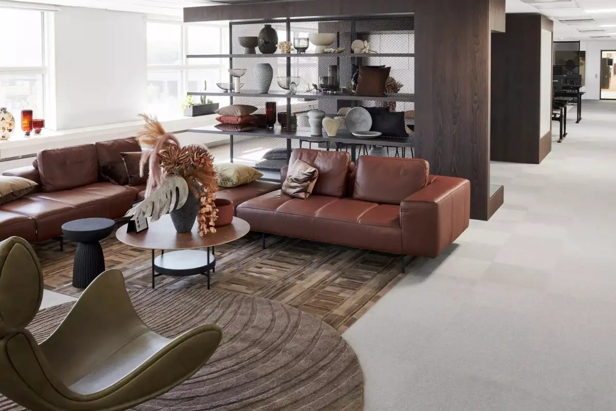 Living room styled by BoConcept with brown leather sofas, a lounge chair, modern coffee tables, and open shelving units