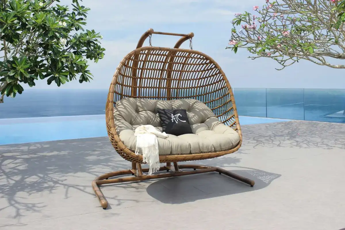 HAVANA double outdoor swing chair with woven HDPE rattan frame and thick beige cushions beside a luxury pool