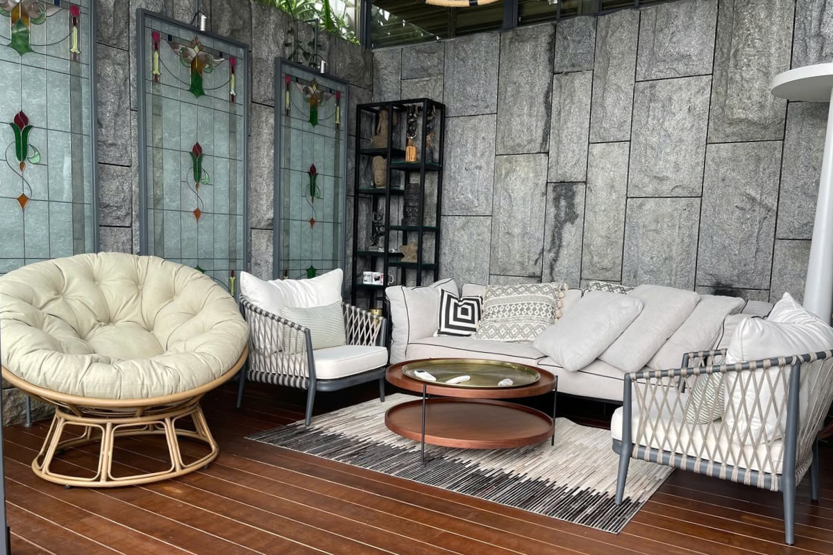 Luxury outdoor lounge area with modular sectional sofa, woven armchairs, and round coffee table
