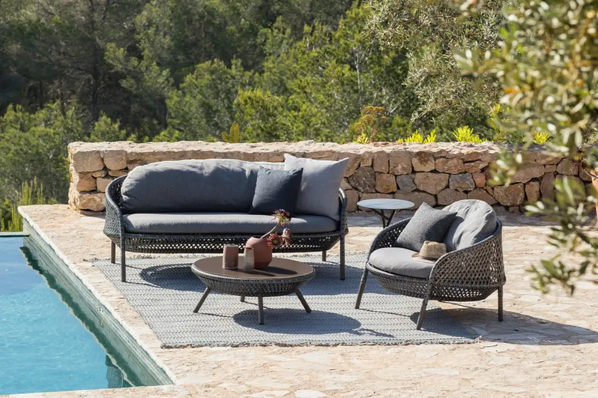 Bộ ghế ngồi ngoài trời thanh lịch của Dedon với sofa, ghế tay vịn và bàn cà phê, mang đến không gian ngoài trời sang trọng và thoải mái