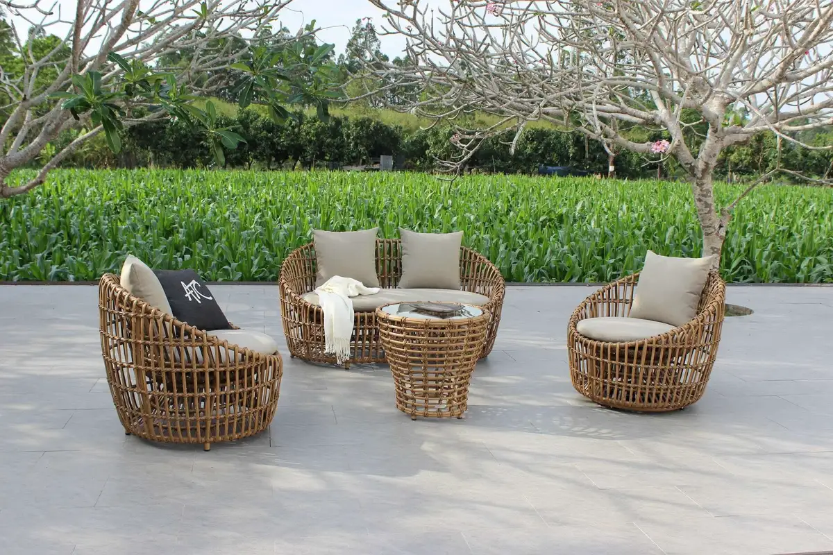 Bộ ghế mây ngoài trời với ghế đệm và bàn trà, được sắp xếp trong một không gian vườn mở