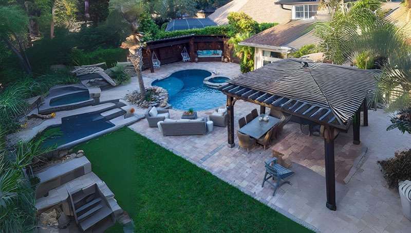 Spacious backyard with a pool, furniture, and pergola.