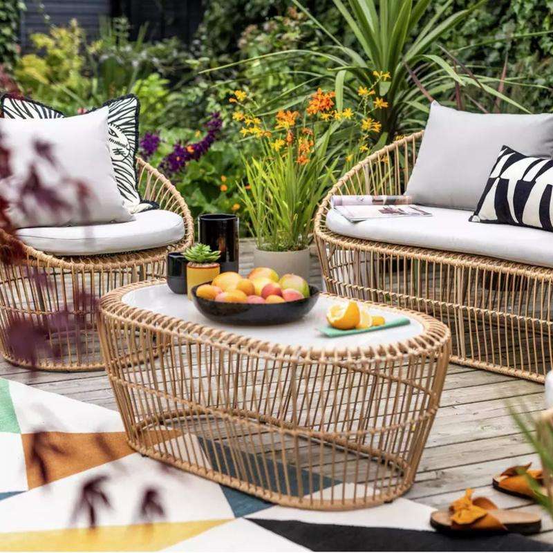 Garden patio with modern rattan chairs and glass table.