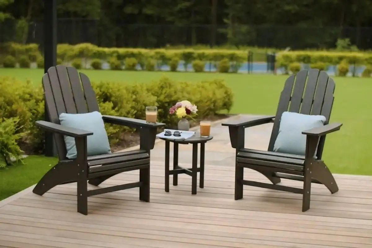 Bộ ghế ngoài trời với hai chiếc ghế tựa lưng kiểu Adirondack và một bàn nhỏ, được đặt trên sàn gỗ, tạo không gian thư giãn ngoài trời.