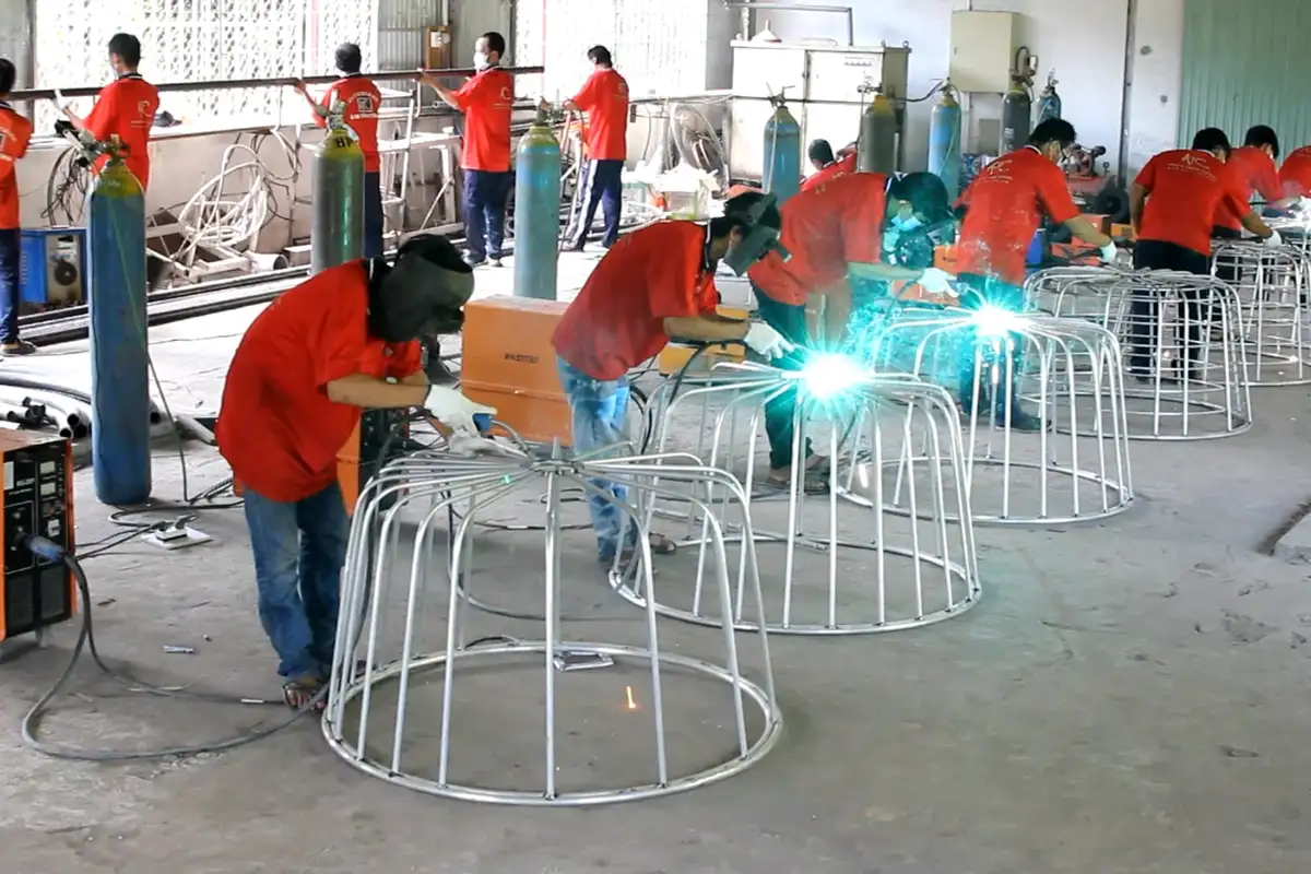 Công nhân trong xưởng sản xuất mây nhựa đang hàn khung ghế theo quy trình kiểm soát chất lượng nghiêm ngặt