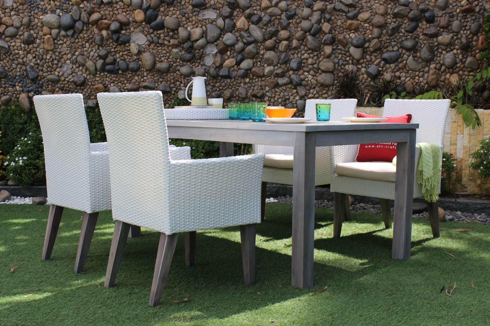 Teak dining set with wicker chairs for a modern outdoor look.