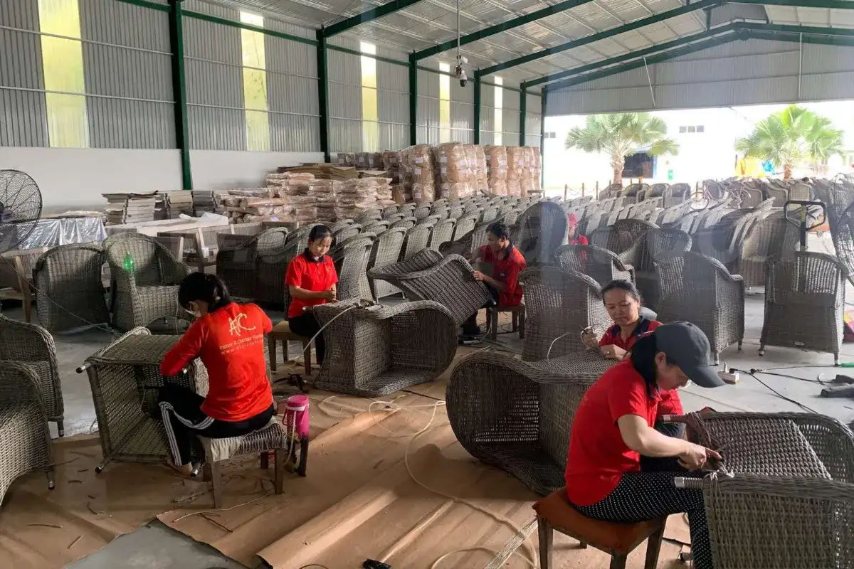 Workers producing woven outdoor furniture inside a large furniture factory
