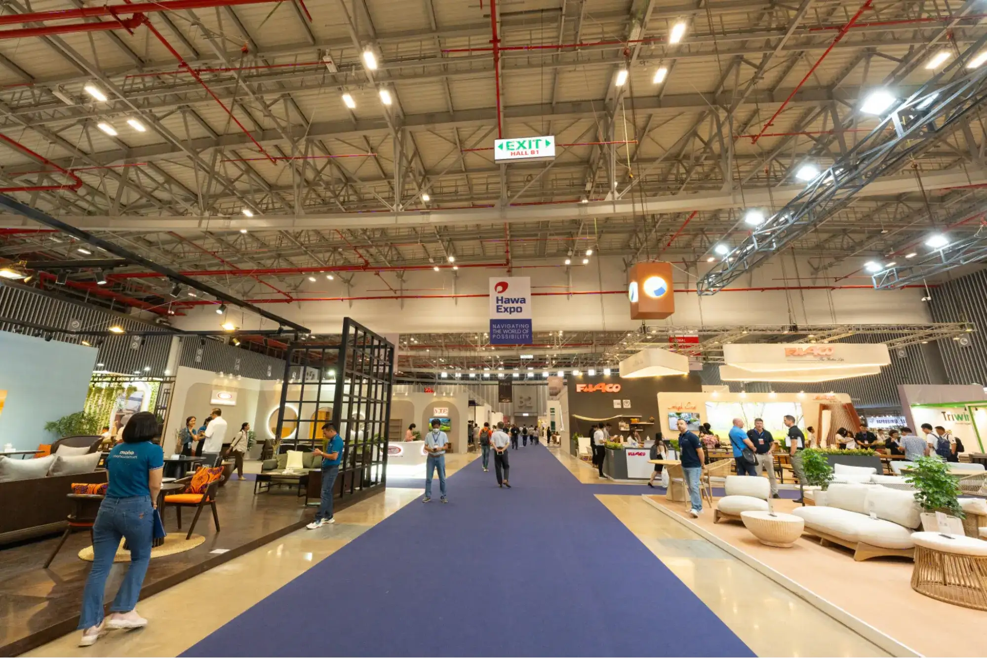 Wide view of HAWA Vietnam furniture exhibition hall in Ho Chi Minh City with furniture booths, walkways, and visitors engaging in B2B sourcing discussions.