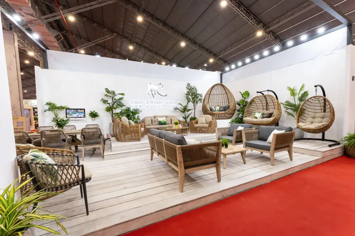  Furniture booth at VIFA Expo fair featuring rattan sofa set, wooden lounge chairs, and hanging egg chairs on display platform