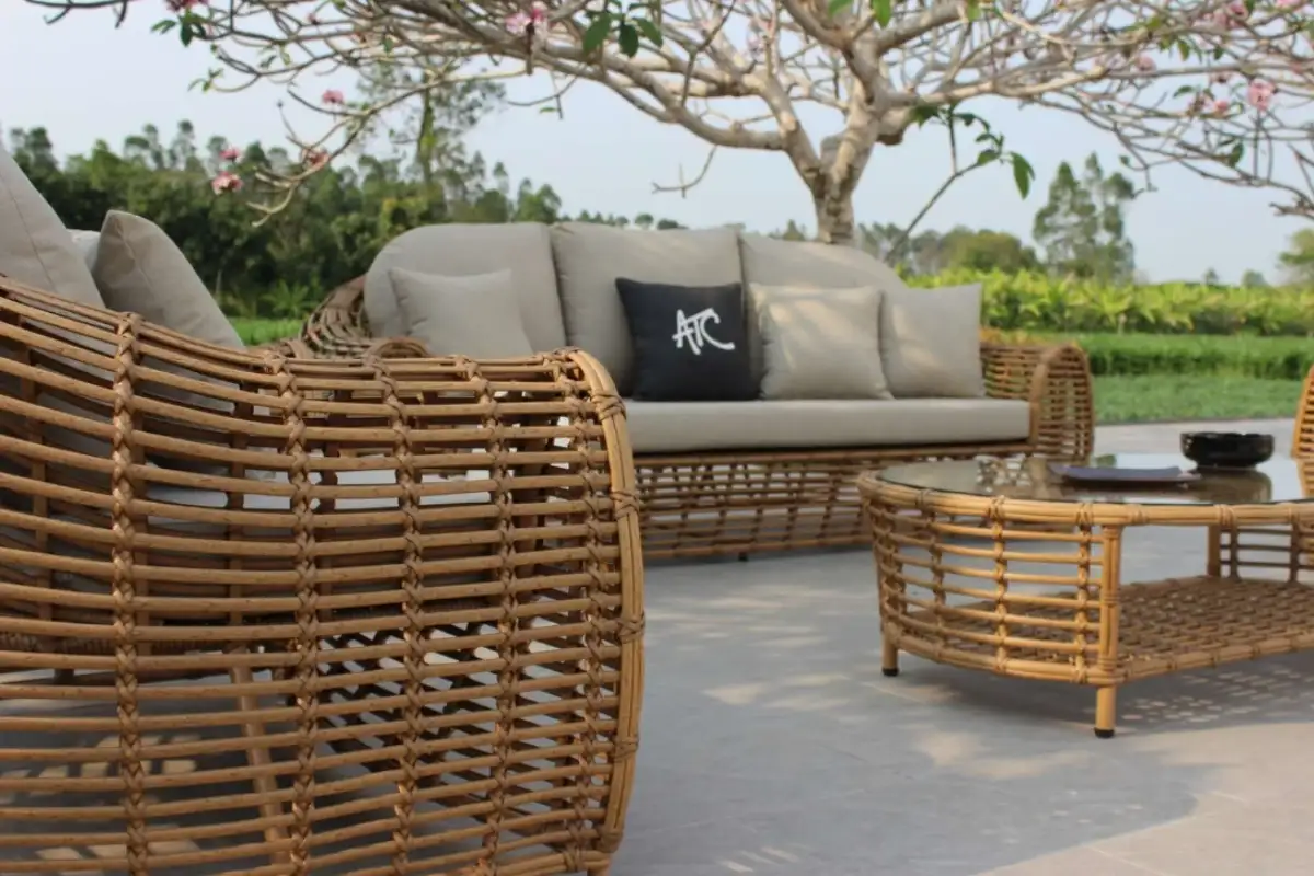 HDPE wicker corner sofa and lounge chairs with cushions placed outdoors in a resortg lounge area.