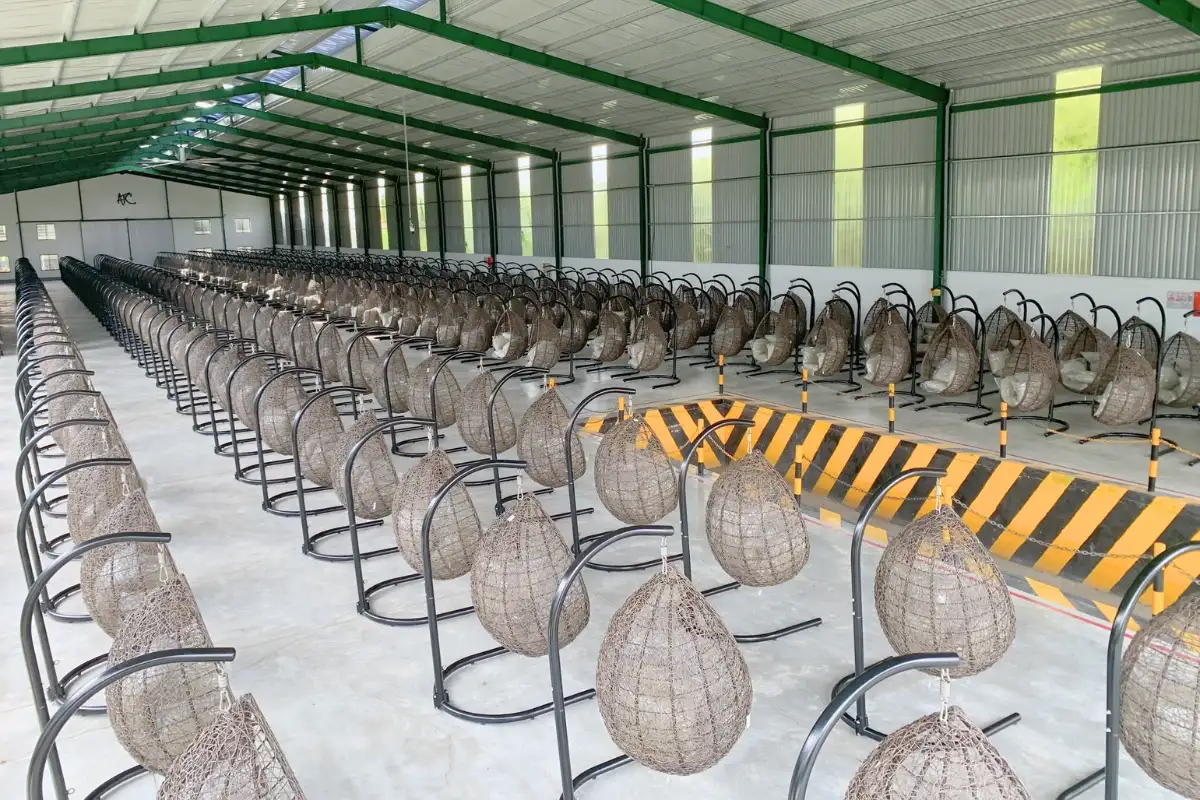 Warehouse stacked neatly with numerous synthetic wicker swing chairs ready for delivery.