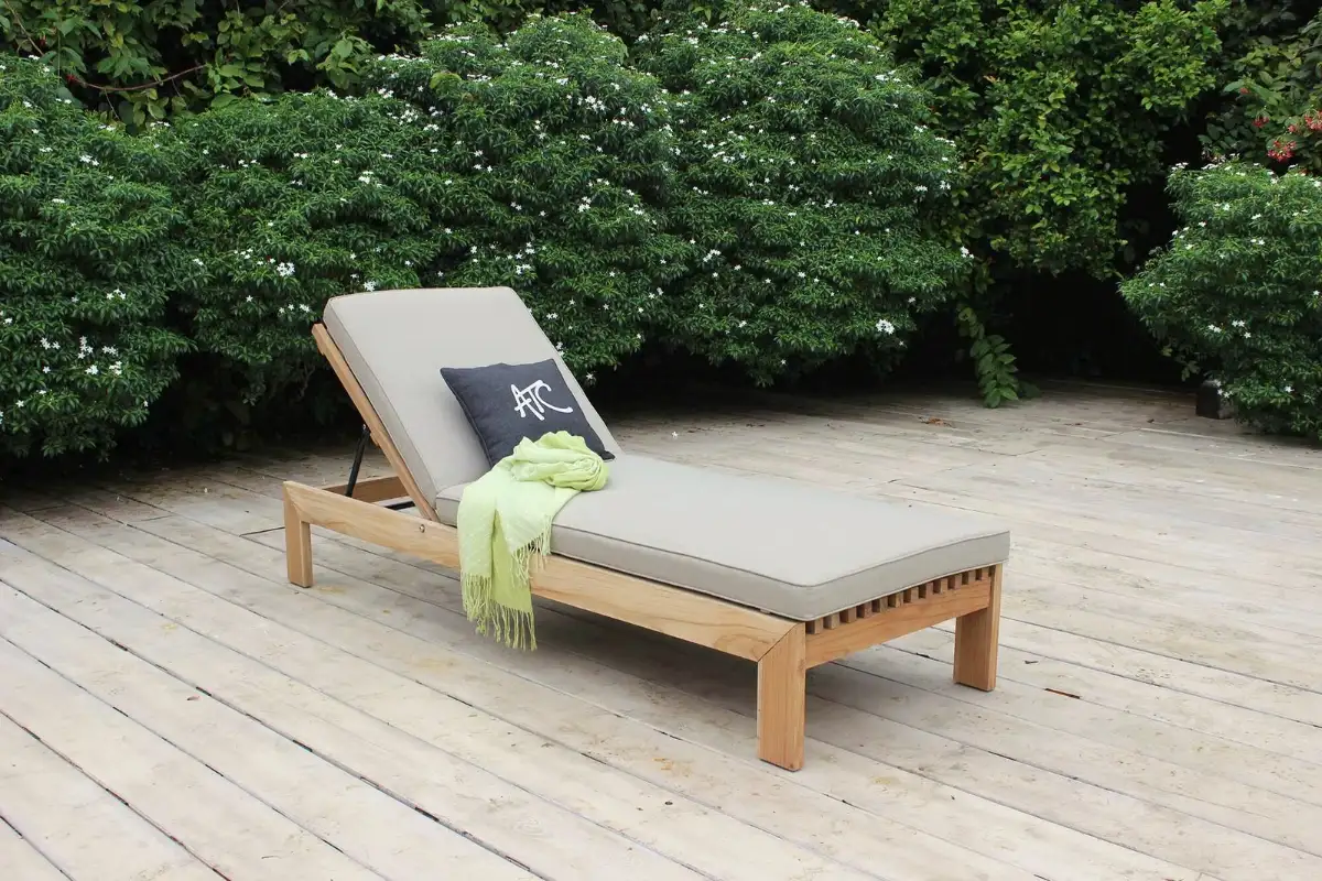 Giường tắm nắng gỗ teak với đệm màu be đặt trên sàn gỗ ngoài trời
