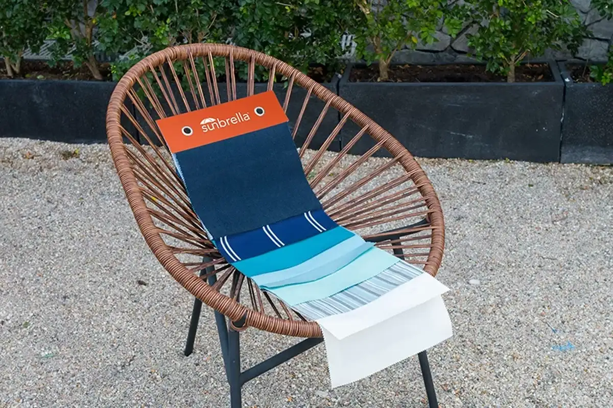 Sample Sunbrella fabrics displayed on a chair, showing durable, UV-resistant materials for hotel outdoor furniture.  
