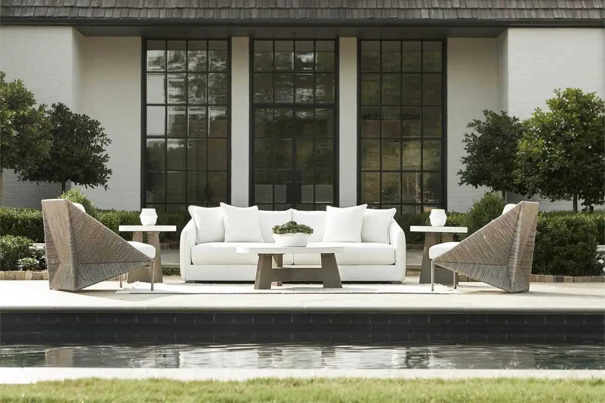 Elegant outdoor seating set by Bernhardt Hospitality featuring a white sofa and modern woven chairs near a pool