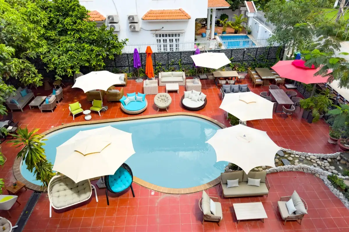 Top view of a vibrant poolside area with eco-inspired outdoor furniture and colorful umbrellas surrounded by greenery
