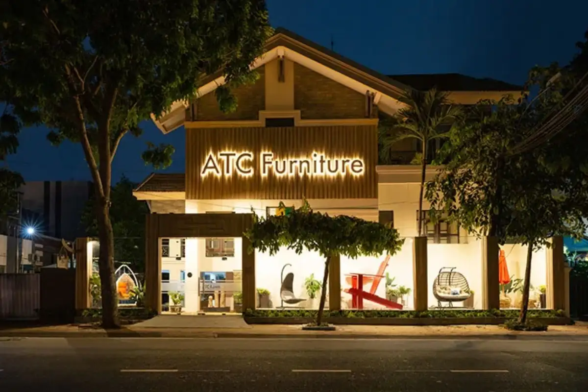 ATC Furniture’s showroom at night, warmly lit and showcasing premium outdoor furniture through its glass facade.
