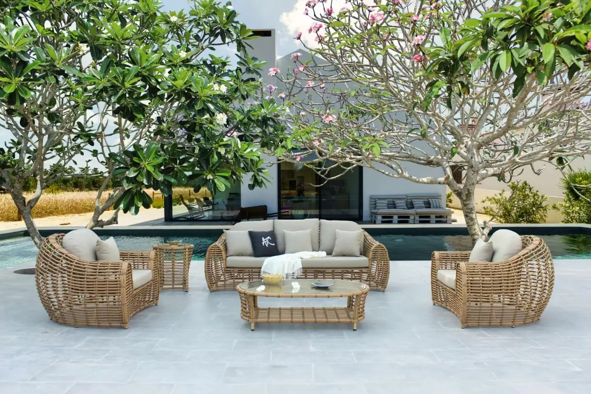  A rattan outdoor furniture set arranged by the poolside under blooming frangipani trees, blending relaxation with resort-style elegance.