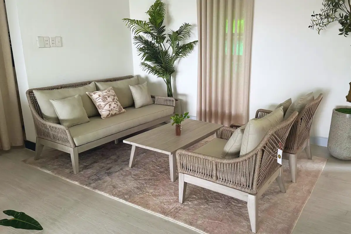 A modern rope-woven furniture set with neutral cushions arranged in a cozy indoor setting, featuring a matching wooden coffee table and soft beige decor.