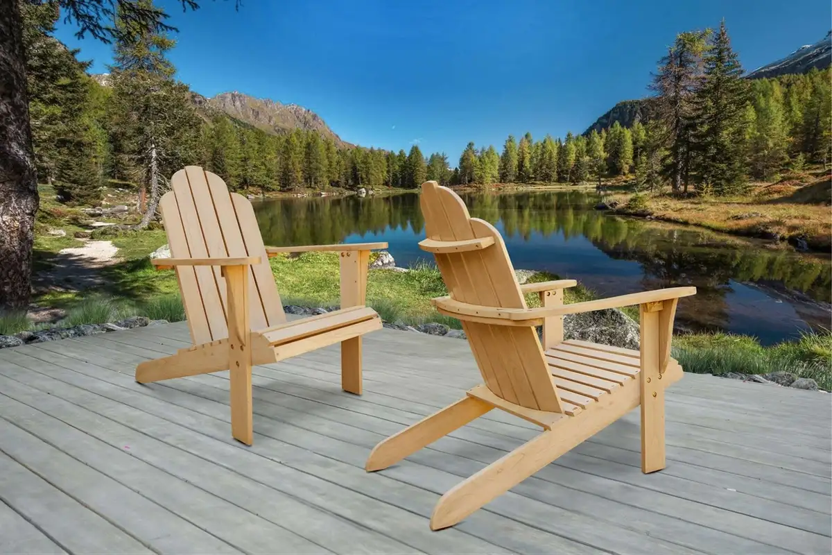 Two wooden Adirondack chairs on a lakeside deck, surrounded by mountains and pine trees, symbolizing relaxation in nature.  