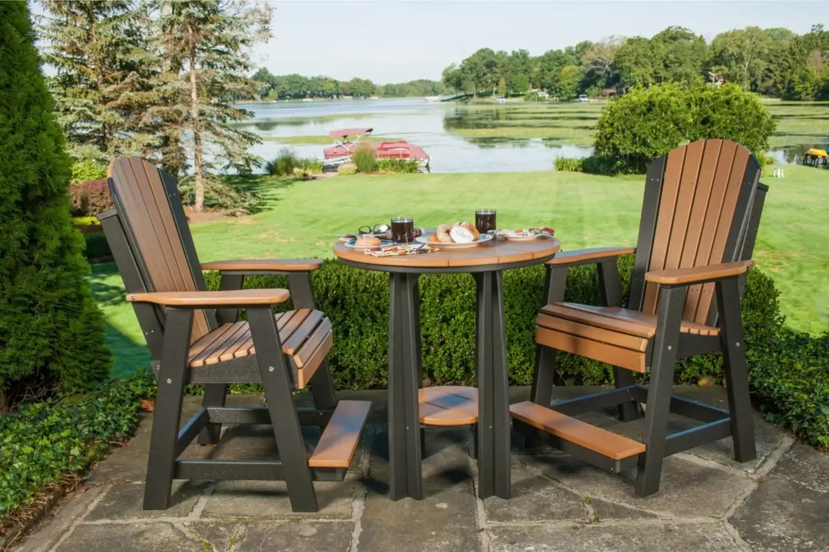 Two tall Adirondack balcony chairs with footrests and a round table set on a patio overlooking a lake.  