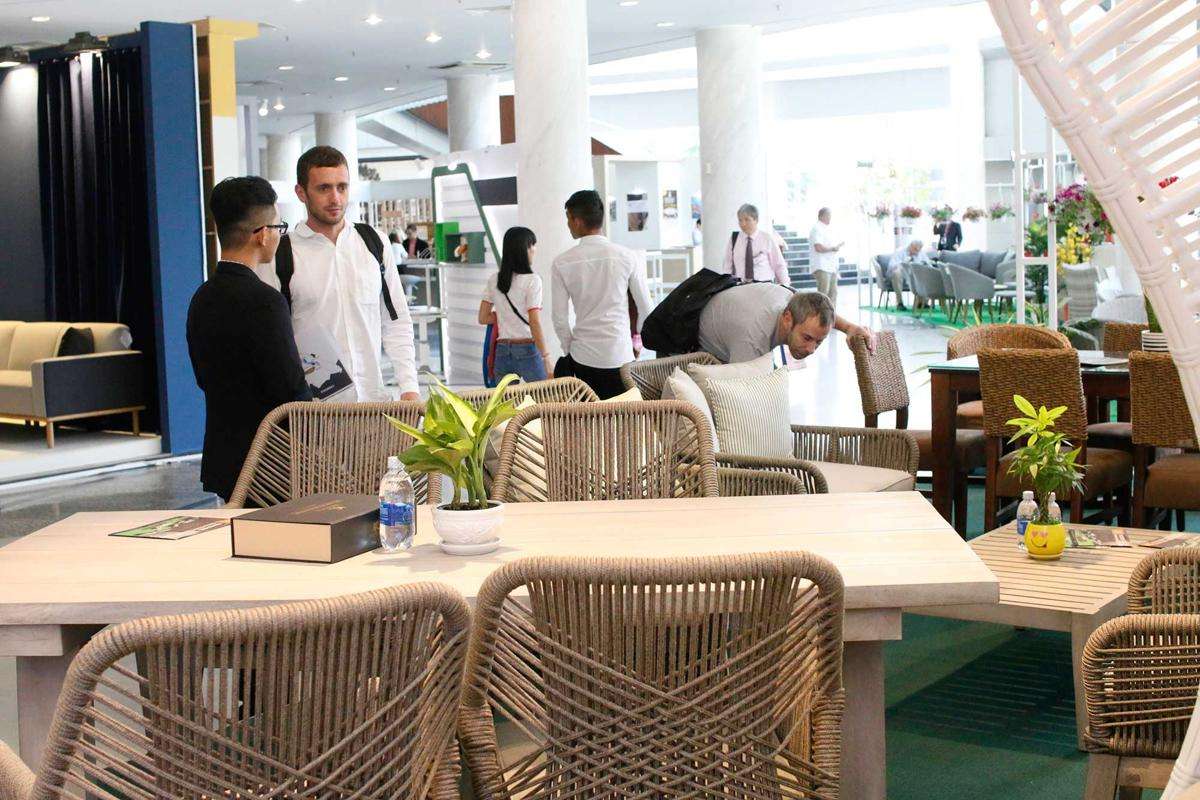 ATC Furniture's elegant display of wicker outdoor furniture in a modern exhibition setting with engaging customer interactions