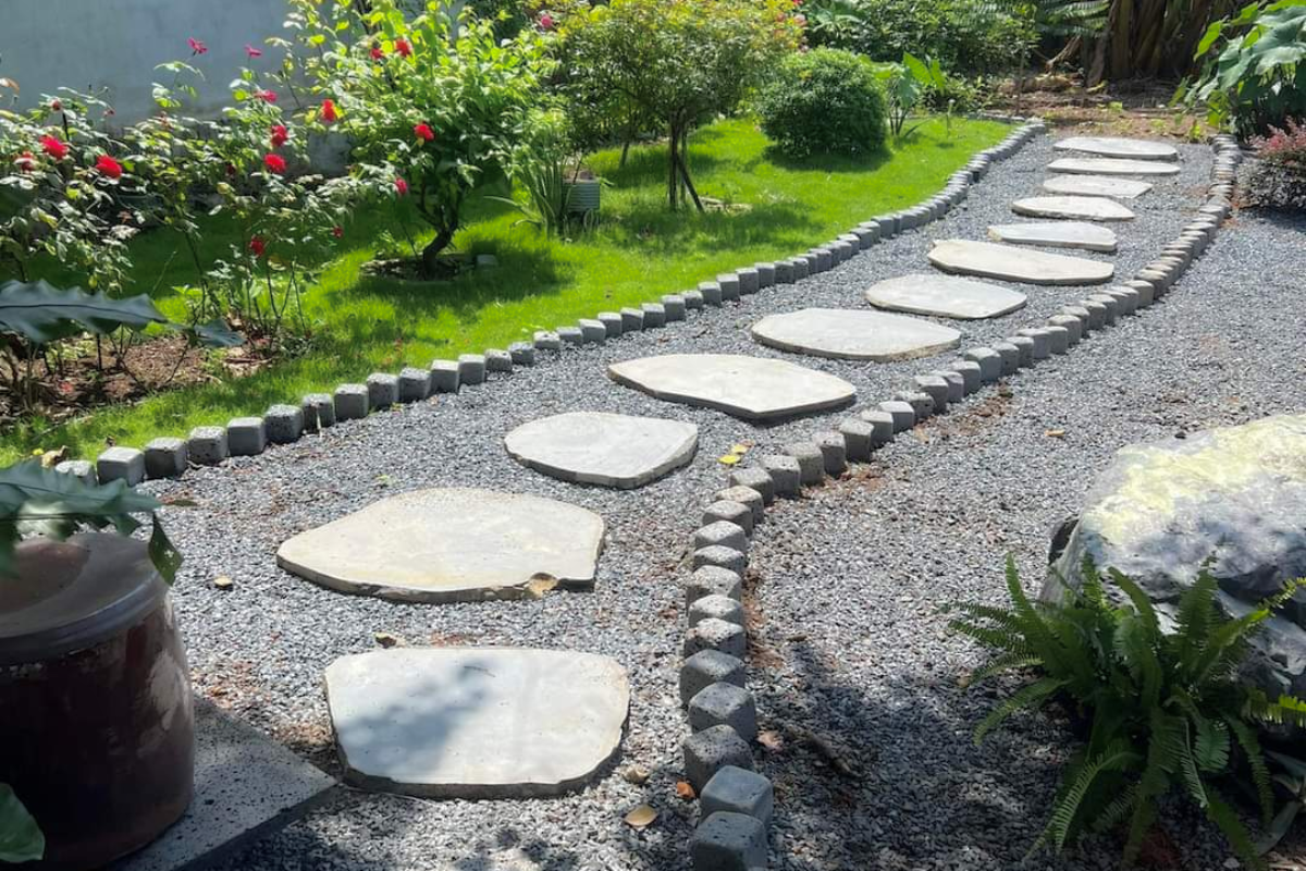 Các phiến đá granite được bố trí thành lối đi uốn cong trong sân vườn với sỏi và cây xanh