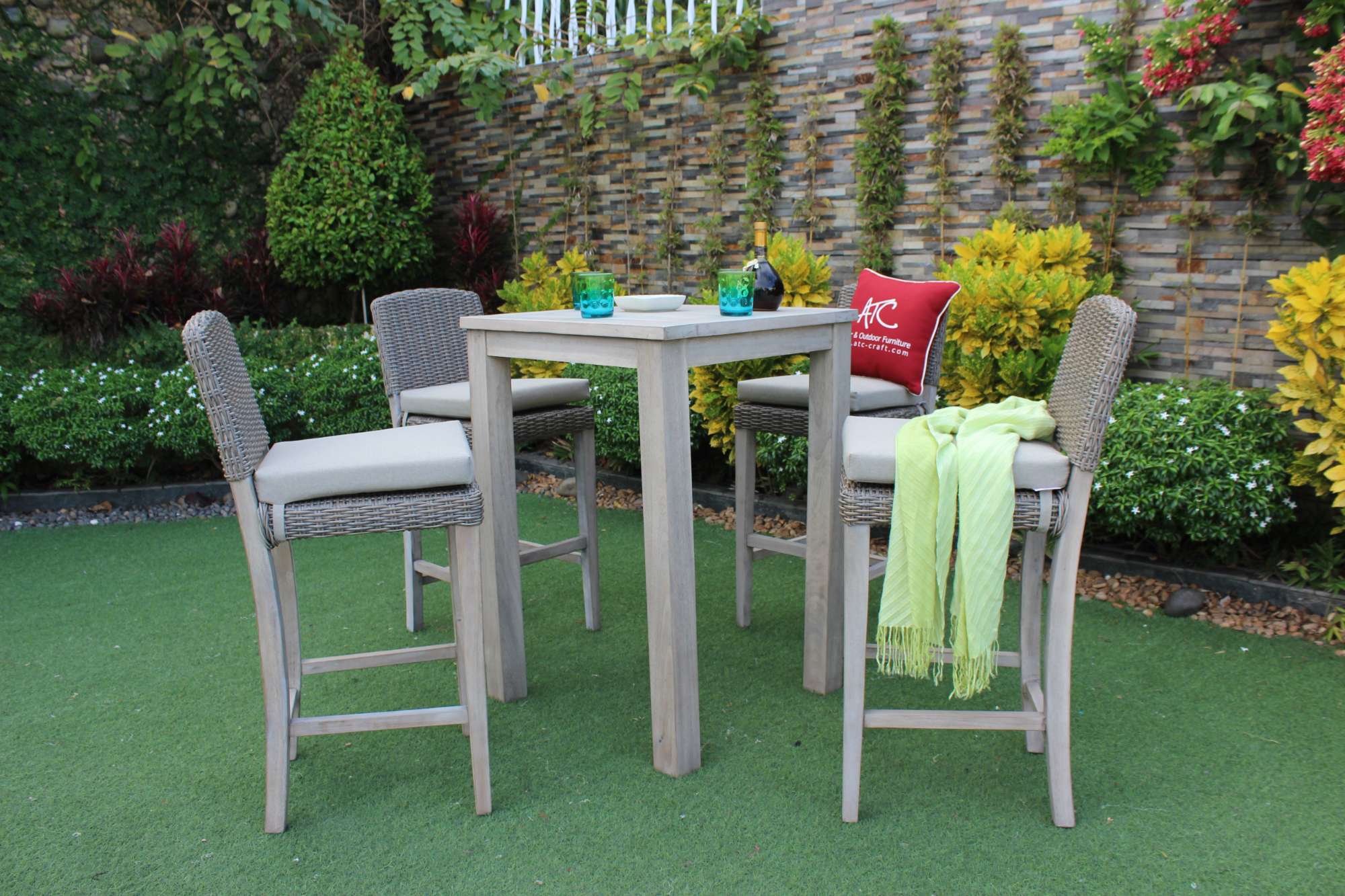 A tall wooden table and wicker bar set with plush red cushions, creates a perfect setting for coffee breaks