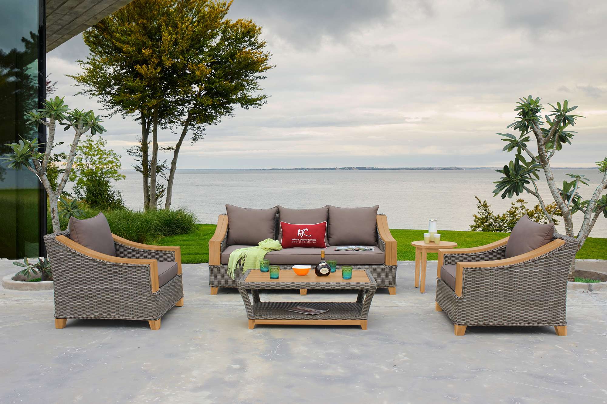 Outdoor dining set with wicker chairs on a wooden deck by the lake.