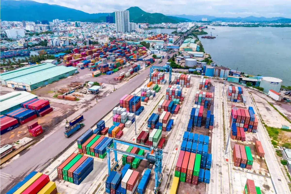 A panoramic view of Quy Nhon Port with colorful shipping containers and cranes, highlighting its role as a major export hub for outdoor and wicker furniture in Vietnam.