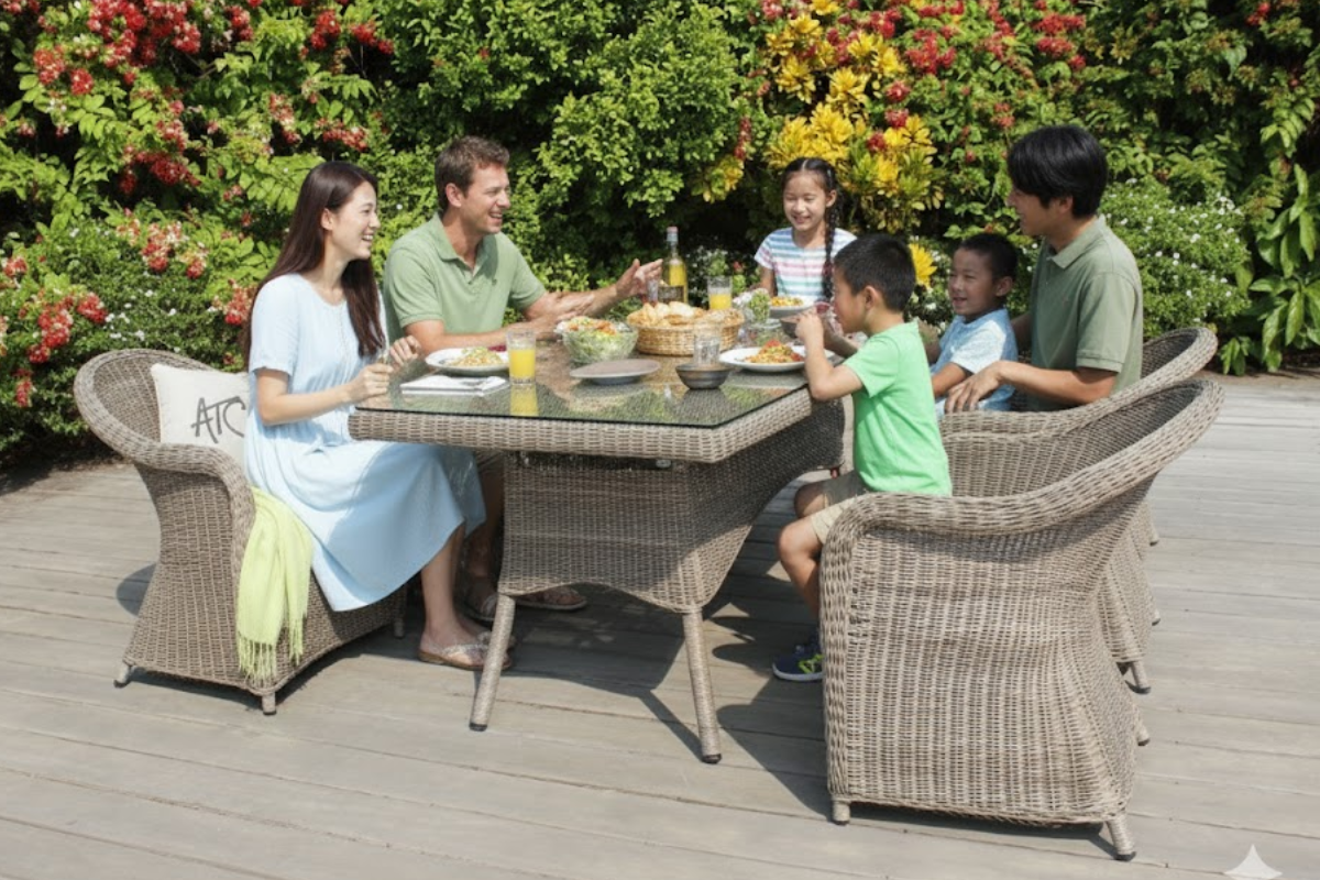 Một gia đình quây quần bên bộ bàn ăn mây ngoài trời trong khu vườn xanh mát, toát lên hơi ấm và vẻ đẹp tự nhiên.