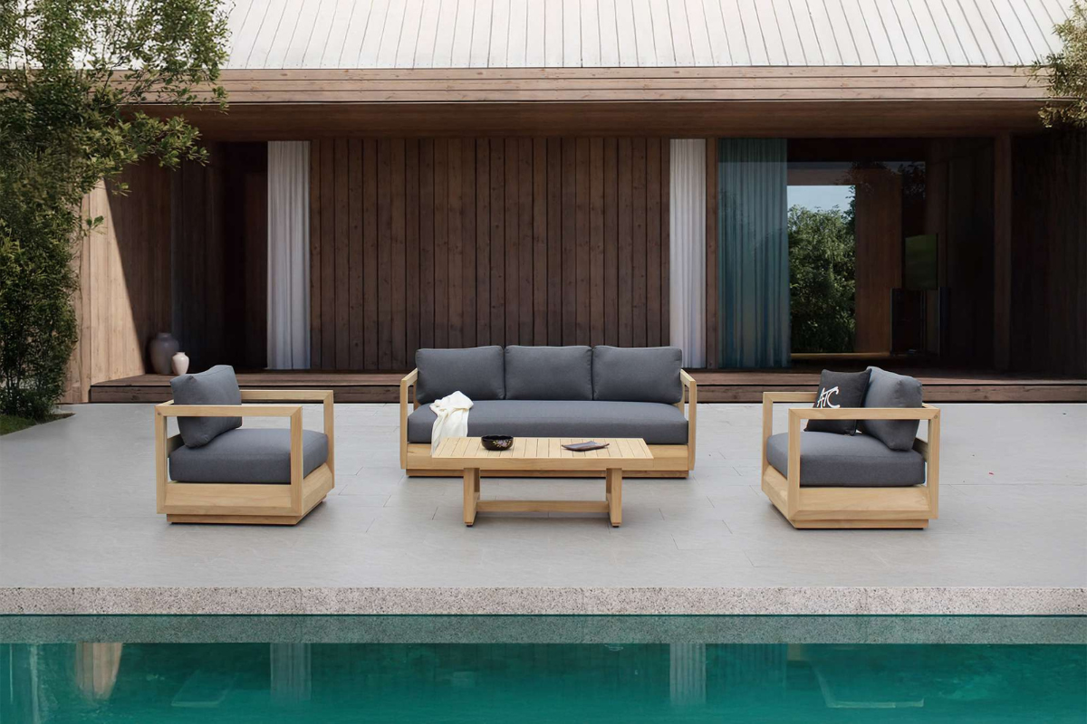 Bộ sofa MAJORCA với khung gỗ teak nguyên khối và nệm dày màu ghi, bố trí trên sân hiên cạnh hồ bơi.