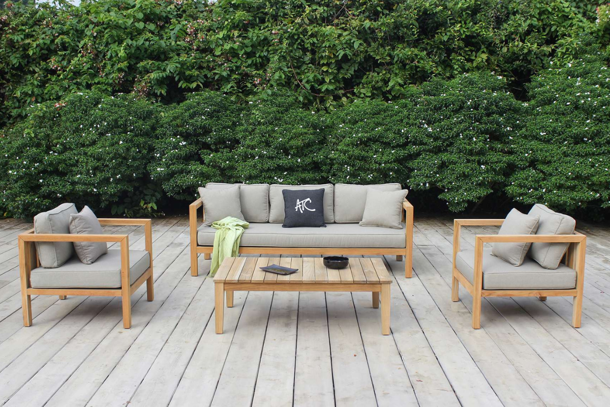 Bộ bàn ghế APOLLO nổi bật với khung teak và nệm êm, đặt trên sàn gỗ rộng bao quanh bởi thảm cây xanh.