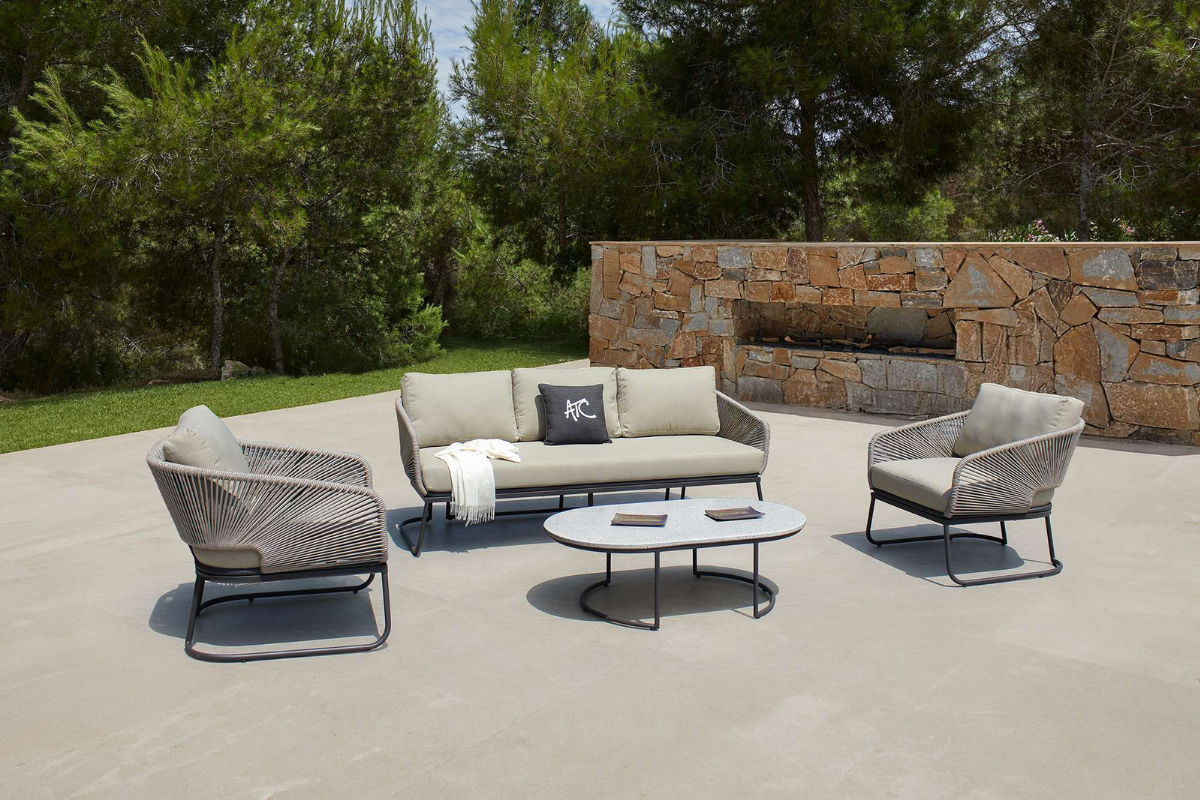 Bộ sofa CORSICA ngoài trời với ghế rope, nệm dày 20cm và bàn nhôm, bố trí trên sân hiên gần bức tường đá.