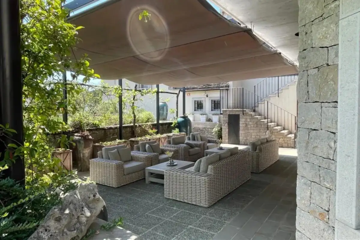 Khu vực thư giãn ngoài trời phong cách tối giản với bộ sofa mây đan, đệm tông trung tính và mái che lớn trong sân hiện đại